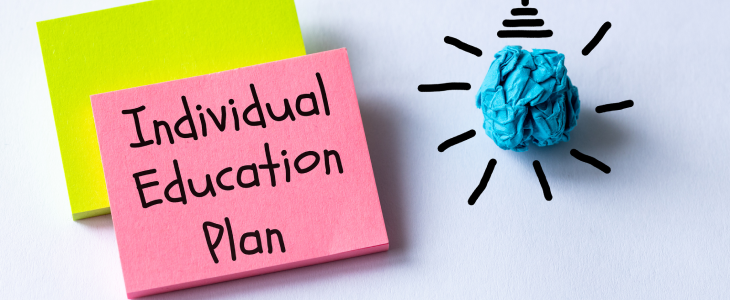 Post it note with Individual Education Plan (IEP) next to a cartoon light bulb